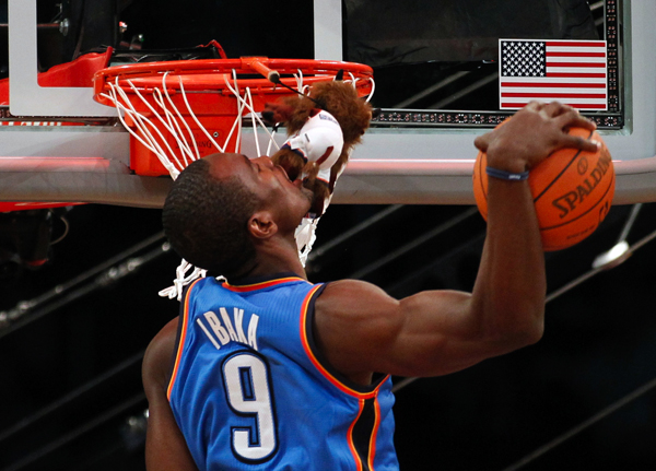 Thunder's Ibaka grabs a stuffed animal with his mouth while competing in the slam dunk contest during the NBA basketball All-Star weekend in Los Angeles