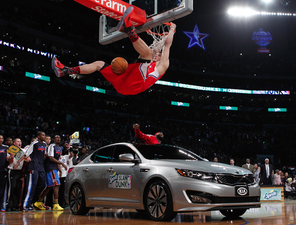 Los Angeles Clippers' Blake Griffin hangs on the rim after jumping over a car in Los Angeles.