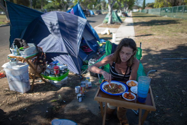 Stacie McDonough, 51, eats lunch by her tent in a homeless RV and tent encampment near LAX airport in Los Angeles, California, United States, October 26, 2015. McDonough is an army veteran with a college degree who has been homeless for almost 2 weeks. Los Angeles officials last month declared the rising problem of homelessness an "emergency" in the city and proposed spending $100 million to provide permanent housing and shelters to help the city's 26,000 indigent. The nation's second-largest city has nearly 18,000 individuals living on the streets, as opposed to shelters. REUTERS/Lucy Nicholson