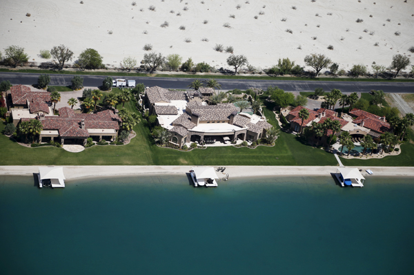 Homes with boathouses built around an artificial lake are seen in Indio, California April 13, 2015. California's cities and towns would be required to cut their water usage by up to 35 percent or face steep fines under proposed new rules, the state's first-ever mandatory cutbacks in urban water use as the state enters its fourth year of severe drought. Communities where residential customers use more than 165 gallons of water per person per day would have to cut back by 35 percent. Picture taken April 13, 2015. REUTERS/Lucy Nicholson - RTR4XD3S