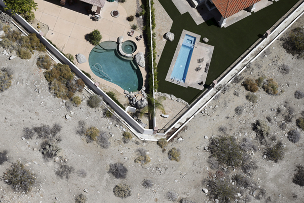Swimming pools are seen behind homes in Palm Springs, California April 13, 2015. The average daily water usage per person in Palm Springs is 201 gallons, more than double the California average, according to the New York Times. California's cities and towns would be required to cut their water usage by up to 35 percent or face steep fines under proposed new rules, the state's first-ever mandatory cutbacks in urban water use as the state enters its fourth year of severe drought. Communities where residential customers use more than 165 gallons of water per person per day would have to cut back by 35 percent. Picture taken April 13, 2015. REUTERS/Lucy Nicholson - RTR4XD7X